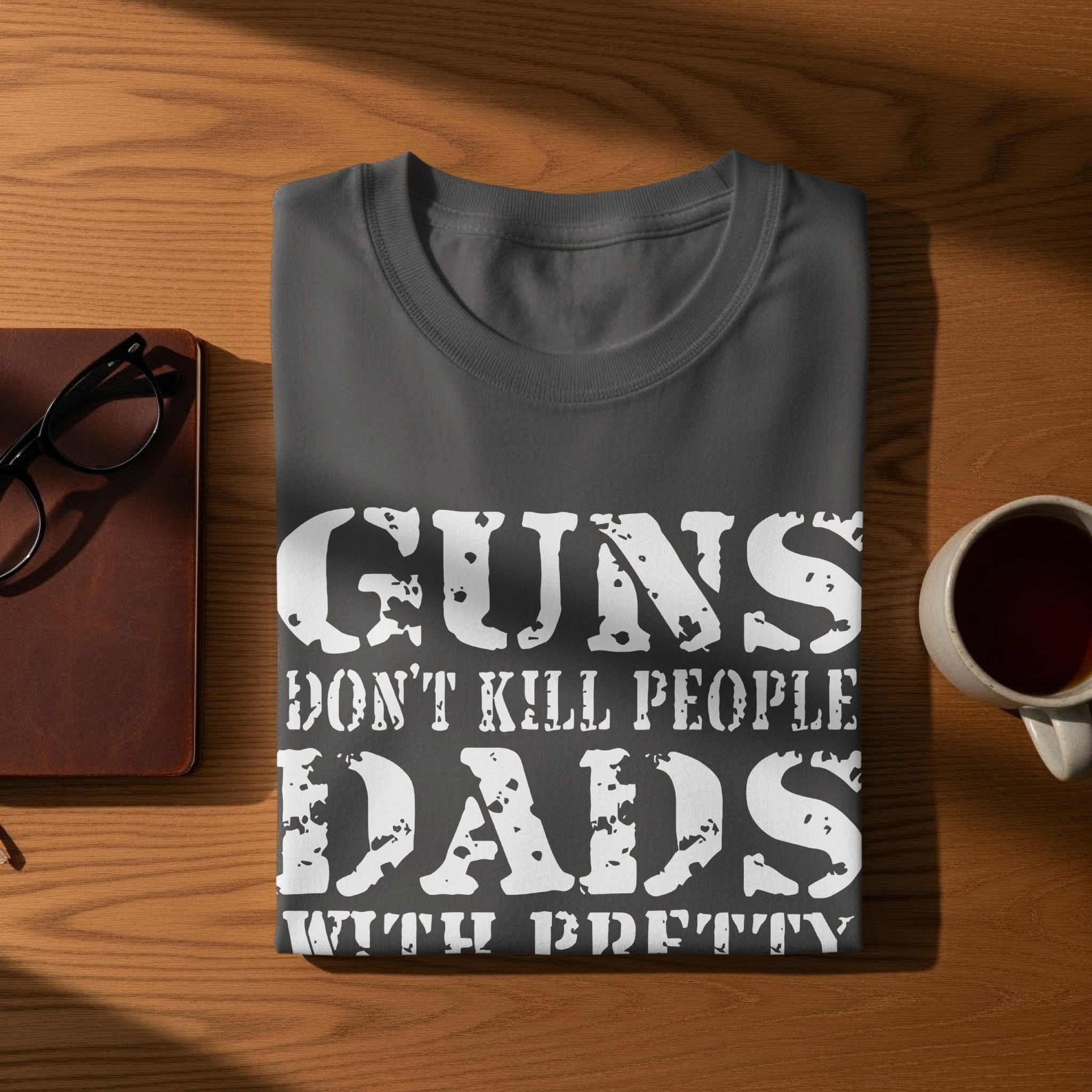 Dark grey t-shirt with "GUNS DON'T KILL PEOPLE DADS WITH PRETTY DAUGHTERS DO" printed on it.